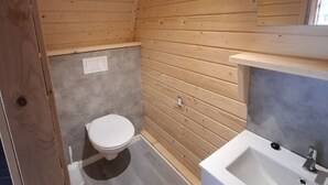 Un bagno piccolo rivestito in legno, con il water e un lavandino.
