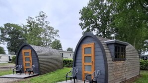 Due piccole cabine semicircolari con porte e finestre in legno, ciascuna con un set di sedie all'esterno.