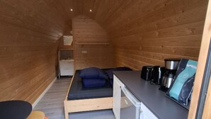 Un interno compatto in legno, con un letto, un tavolino e un angolo cottura.