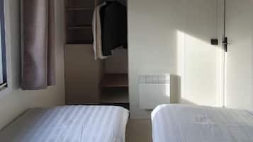 Une chambre d’hôtel avec deux lits, une armoire et un radiateur.