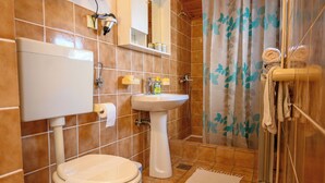 A bathroom with a toilet, sink, and shower. - Room Marta (Omisalj)