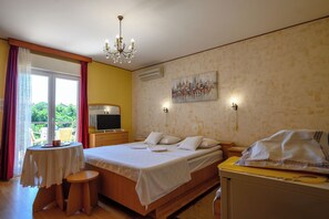 A bedroom with a bed, bedside table, TV, and a painting on the wall. - Room Marta (Omisalj)