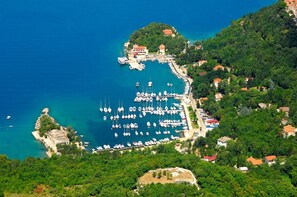 An aerial view of a marina with numerous boats docked, surrounded by lush greenery and residential buildings. - Room Marta (Omisalj)
