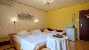 Habitación de hotel con dos camas, una mesita, un refrigerador y un cuadro en la pared.