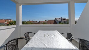 A balcony with a table and chairs, overlooking a residential area. - Apartments Mande (Rab)