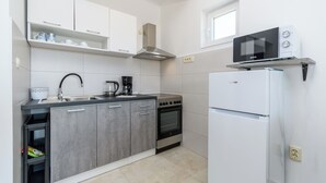 A modern kitchen with a built-in oven, a microwave, a sink, and a refrigerator. - Apartments Mande (Rab)