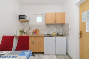A compact kitchen with a microwave, sink, and a small refrigerator. - Apartments Mande (Rab)