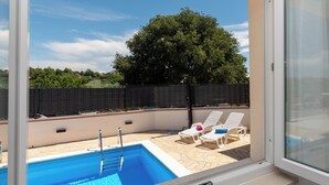 A swimming pool with a diving board, lounge chairs, and a view of a tree and fence. - House Mirakul Near Krka With Private Pool (Skradin)