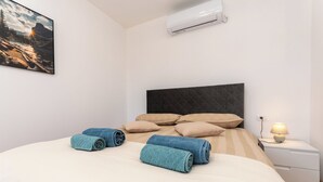 A neatly made bed with rolled towels, a bedside lamp, and a wall-mounted air conditioner. - House Mirakul Near Krka With Private Pool (Skradin)