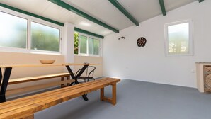 A room with a wooden bench, a table, a chair, and a dartboard on the wall. - House Mirakul Near Krka With Private Pool (Skradin)