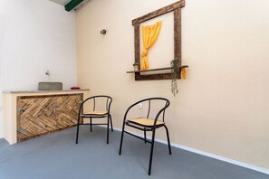 A room with two metal chairs, a wooden cabinet, a small shelf with a plant, and a window with a curtain. - House Mirakul Near Krka With Private Pool (Skradin)