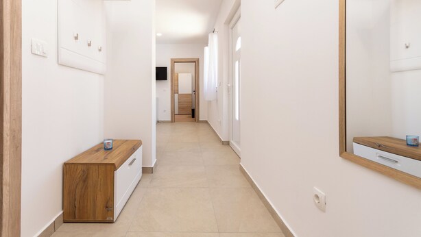 A narrow hallway with a wooden bench, a mirror, and a door at the end. - House Mirakul Near Krka With Private Pool (Skradin)