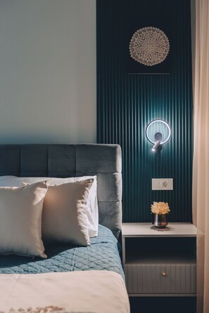 A bedroom with a bed, bedside table, and a wall-mounted light fixture. - Apartments Menigo Manzoni (Punat)