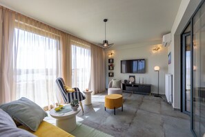 A modern living room with a sofa, armchair, coffee table, and a television mounted on the wall. - Apartments Menigo Manzoni (Punat)