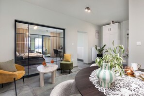 Ein modernes Wohnzimmer mit einer Couch, einem runden Tisch und einem Esstisch mit Spitzenunterlage.