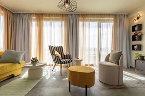 A modern living room with a yellow sofa, striped armchair, round ottoman, and a beige armchair. - Apartments Menigo Manzoni (Punat)