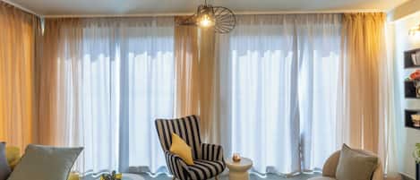 Ein Wohnzimmer mit einem gestreiften Sessel, einem runden Couchtisch mit einem Kaktus und einer Couch.