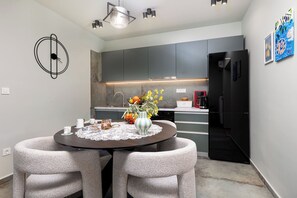 A modern kitchen with grey cabinets, a black refrigerator, and a dining area with a round table and two chairs. - Apartments Menigo Manzoni (Punat)