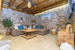 A stone-walled room with a wooden ceiling, a sofa, a coffee table, and a cabinet with a small house model. - House Villa Lara (Vinodol)