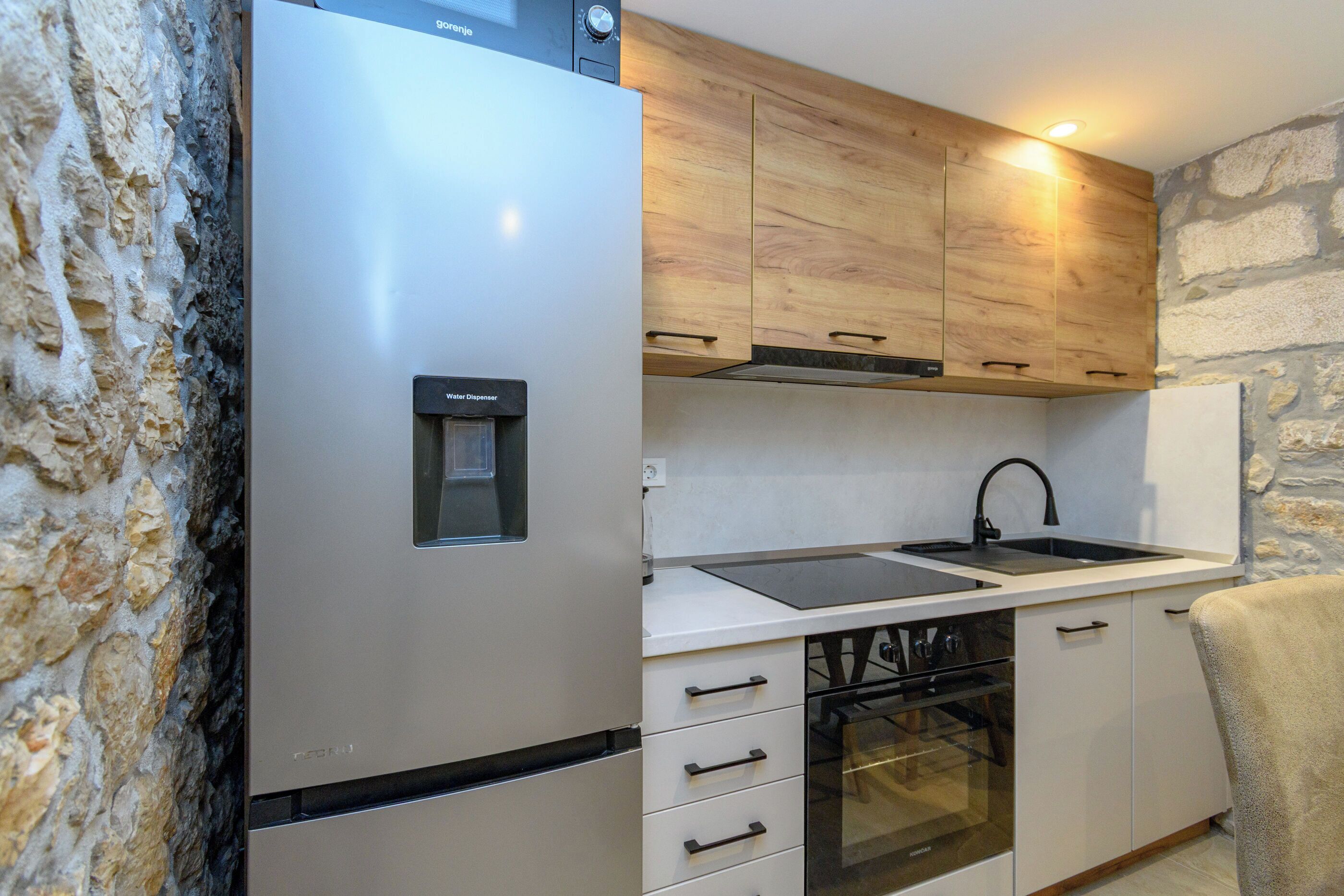 A compact kitchen with a built-in refrigerator, a sink, and a dishwasher.