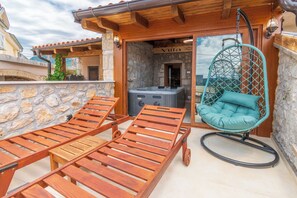 A wooden deck with lounge chairs and a hanging chair, a stone wall, and a sign that reads 'Villa.' - House Villa Lara (Vinodol)