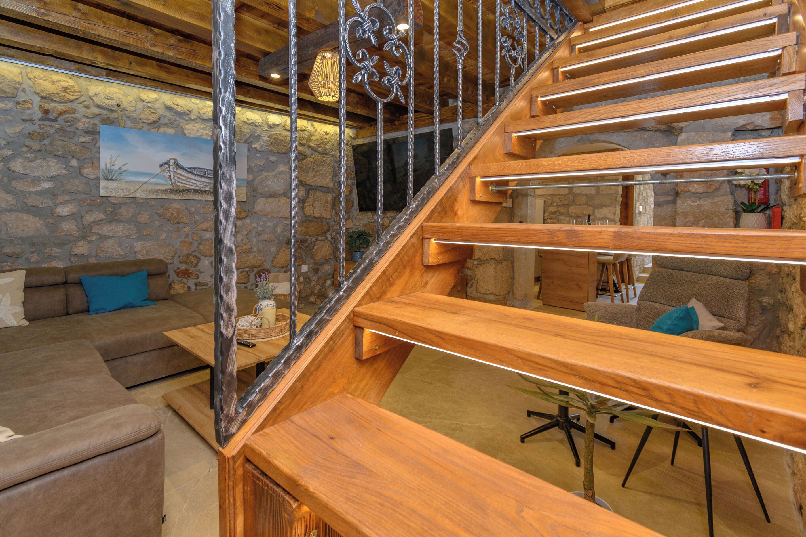 A wooden staircase with metal railings, a stone wall, and a painting.