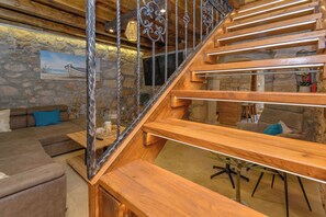 A wooden staircase with metal railings, a stone wall, and a painting. - House Villa Lara (Vinodol)