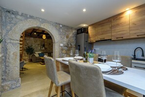 A dining area with a stone archway, wooden cabinets, and a modern kitchen in the background. - House Villa Lara (Vinodol)