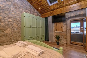 A bedroom with stone walls, wooden ceiling, a bed with folded towels, a green wardrobe, a potted plant, and a view through a door. - House Villa Lara (Vinodol)