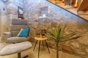 A stone wall interior with a cushioned chair, a small round table, and a potted plant. - House Villa Lara (Vinodol)