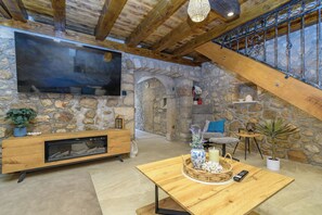 A spacious living area with a stone wall, wooden furniture, a fireplace, and a large flat-screen TV. - House Villa Lara (Vinodol)