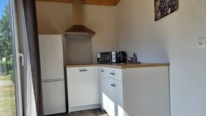 A compact kitchen with white cabinets, a microwave, and a coffee maker. - Cube chalet voor 4 personen | De Otterberg (Wijster)