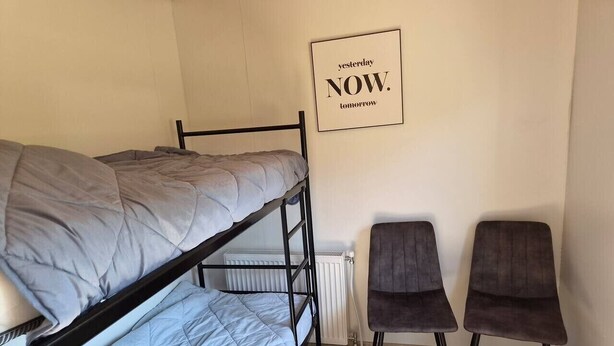 A bunk bed room with a radiator, two chairs, and a motivational poster on the wall. - Cube chalet voor 4 personen | De Otterberg (Wijster)