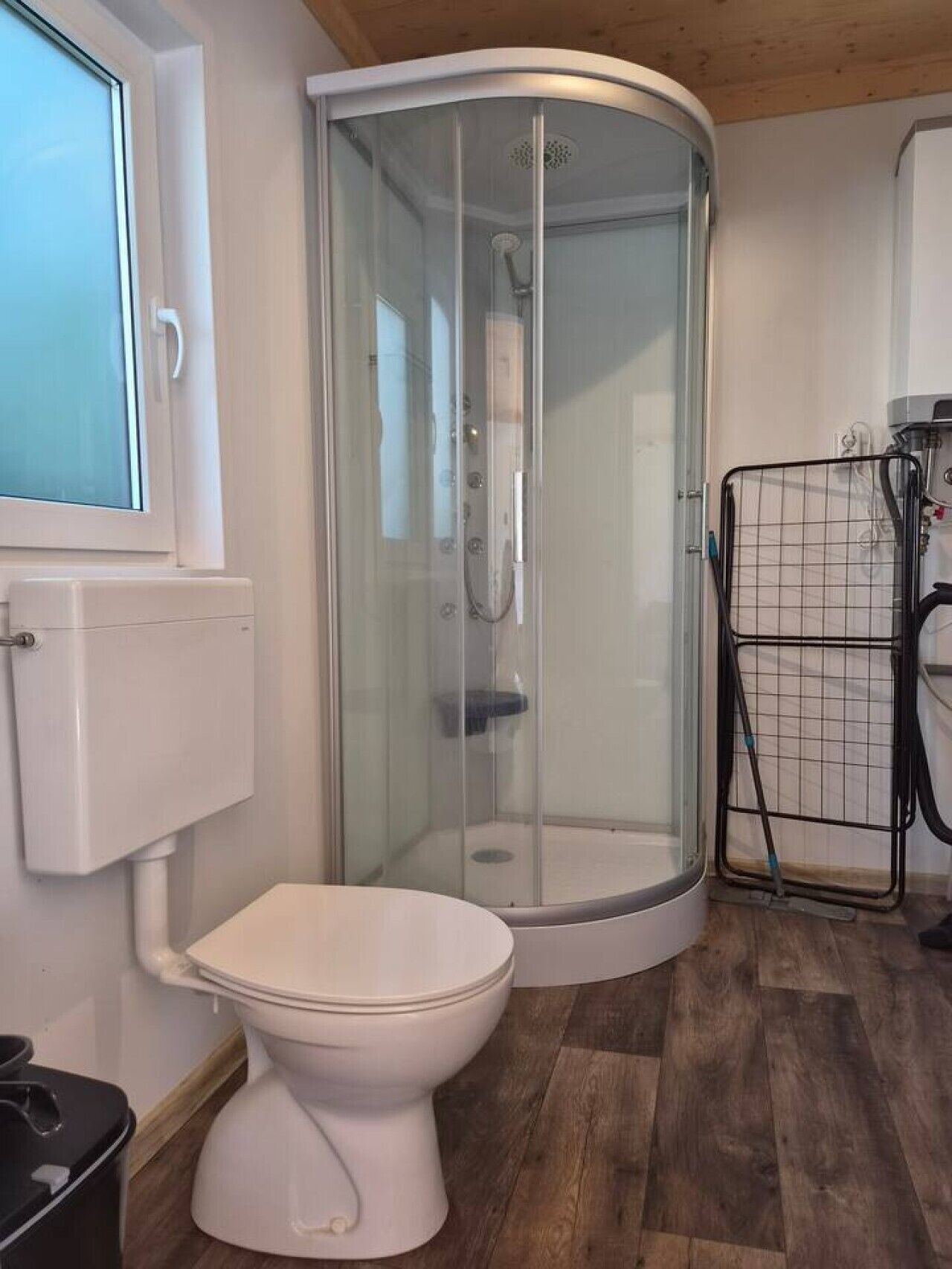 Een badkamer met een douchecabine, een toilet en een raam.
