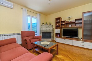 A living room with a fireplace, a television, and a sofa. - Apartment Mediterranean (Opatija)
