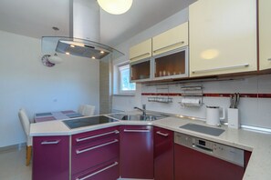 A compact kitchen with a built-in dishwasher, a microwave, and a sink. - Apartment Mediterranean (Opatija)