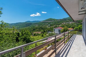 Ein Balkon mit Blick auf ein grünes Tal und ferne Hügel.