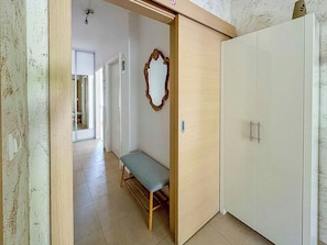A hallway with a bench, a wardrobe, and a mirror. - Apartment Mediterranean (Opatija)