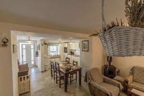 A dining area with a wooden table and chairs, a kitchen in the background, and a wicker lamp. - House Vila Ana (Lopar)