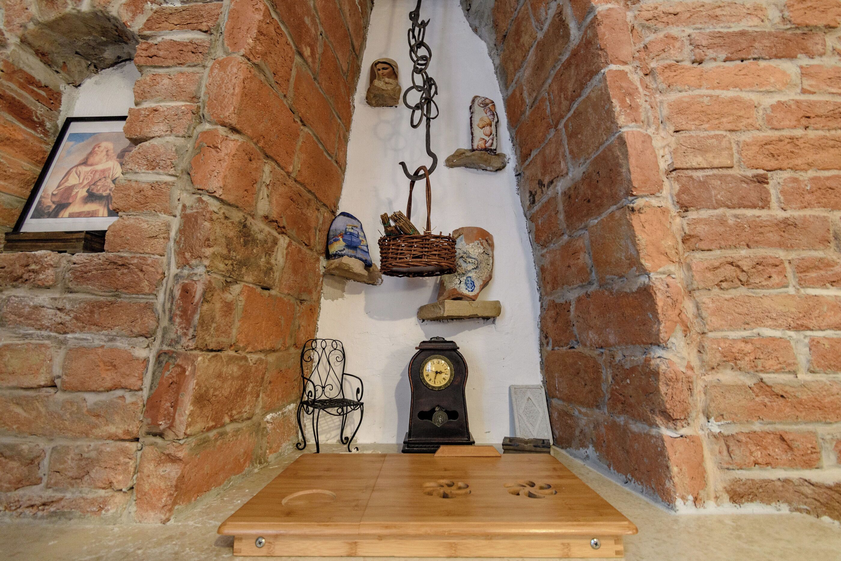 A room with a wooden table, a clock, a chair, and a wall with decorative items.