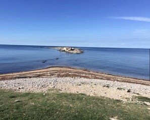 Un paisaje costero con un litoral rocoso, cielo despejado y mar tranquilo.