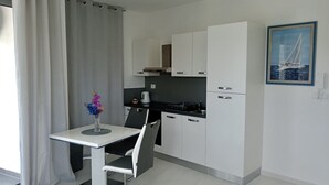 Eine moderne Küche mit weißen Schränken, einem Esstisch mit Stuhl, einer Vase mit Blumen und einem Gemälde an der Wand.