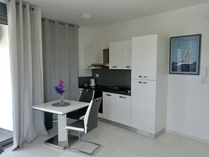 Eine moderne Küche mit weißen Schränken, einem Esstisch mit Stuhl, einer Vase mit Blumen und einem Gemälde an der Wand.