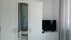 Ein modernes Zimmer mit Kleiderschrank, Fernseher und einer Chandelierleuchtre.