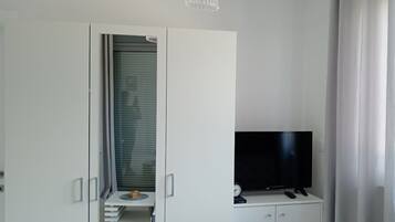 A modern room with a wardrobe, a television, and a chandelier.
