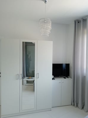 Ein modernes Zimmer mit Kleiderschrank, Fernseher und einer Chandelierleuchtre.