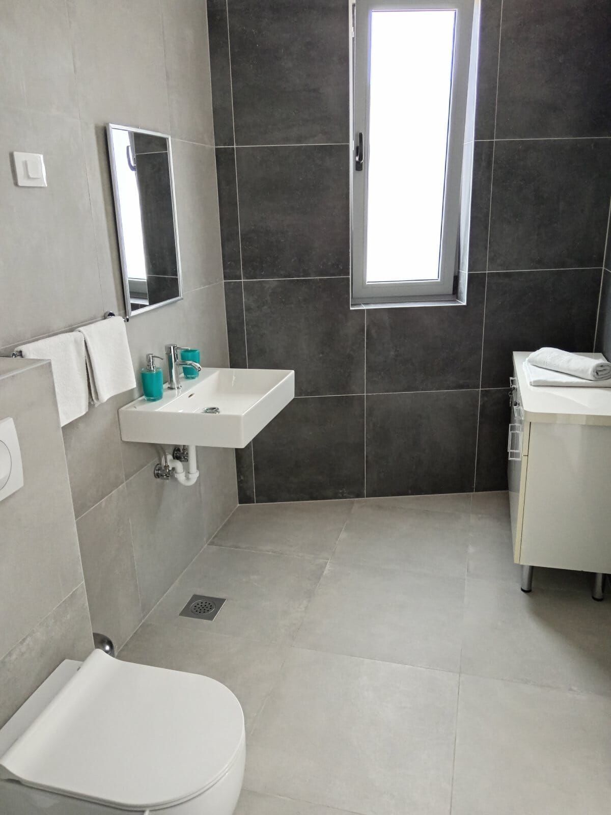 A modern bathroom with a toilet, sink, and mirror.