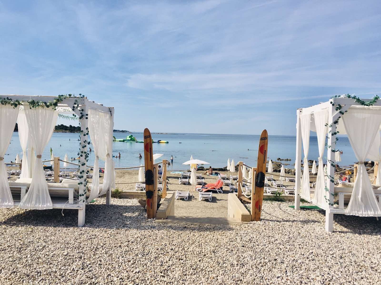 Une cérémonie de mariage organisée sur la plage, avec des auvents blancs et des planches de surf.