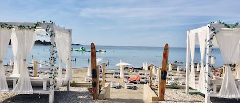 Montaje para una boda en la playa con toldos blancos y tablas de surf.