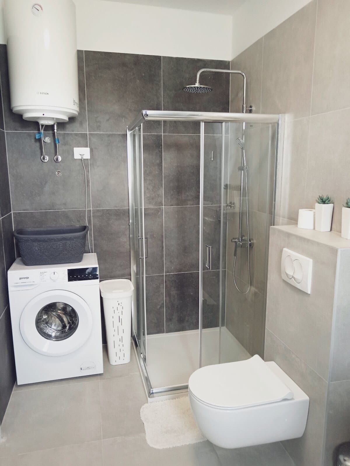 Un bagno compatto con lavatrice, toilette, cabina doccia e lavabo integrato.